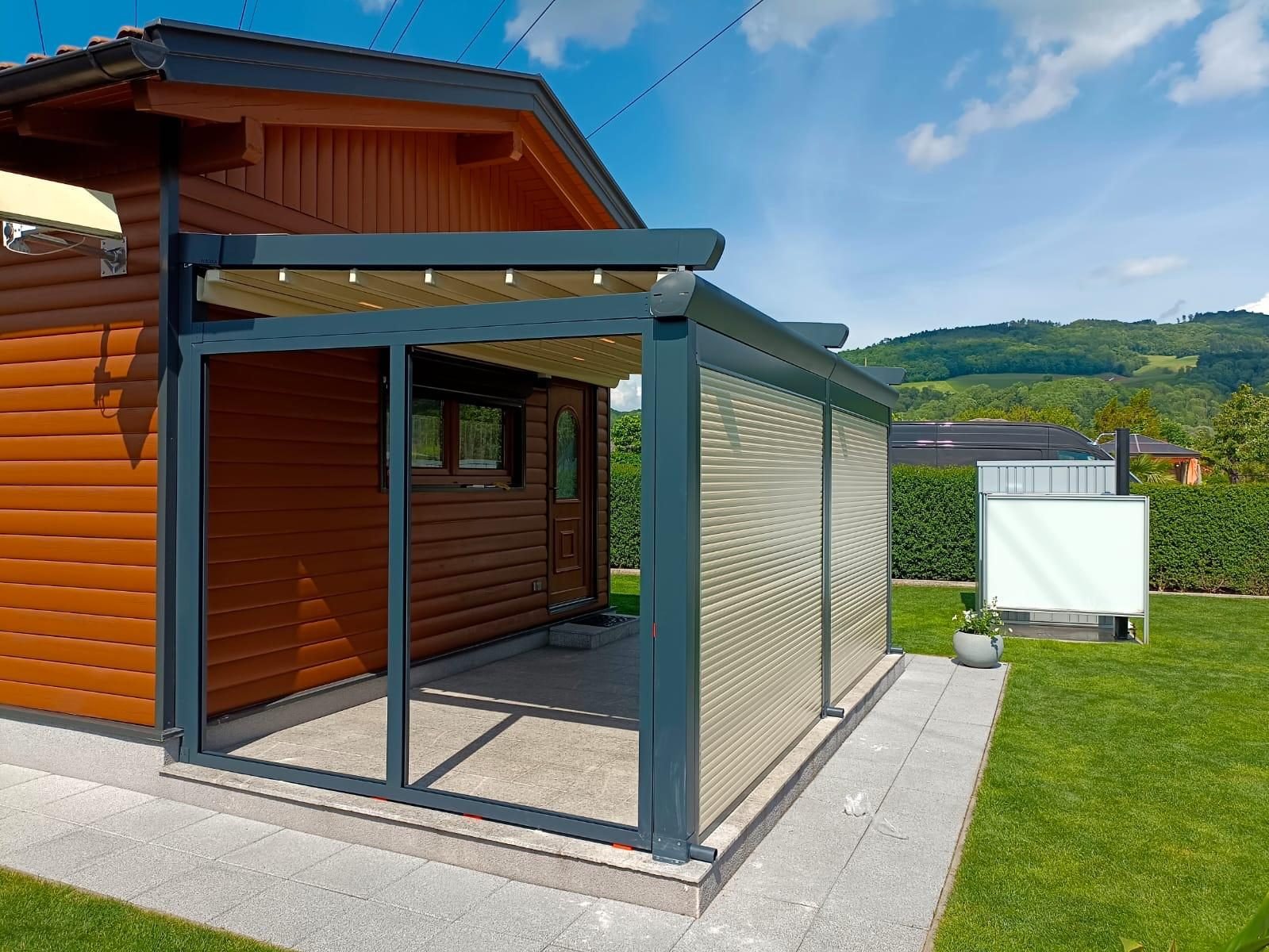 Pergola mit anthrazitfarbenem Gestell an einem Holzhaus, seitlich geschlossen