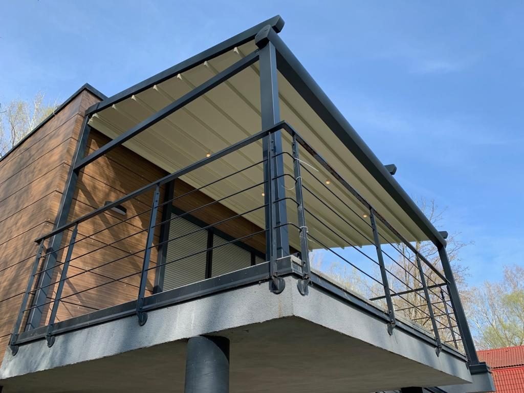 Pergola mit anthrazitfarbenem Gestell über einem Balkon an einem modernen Haus