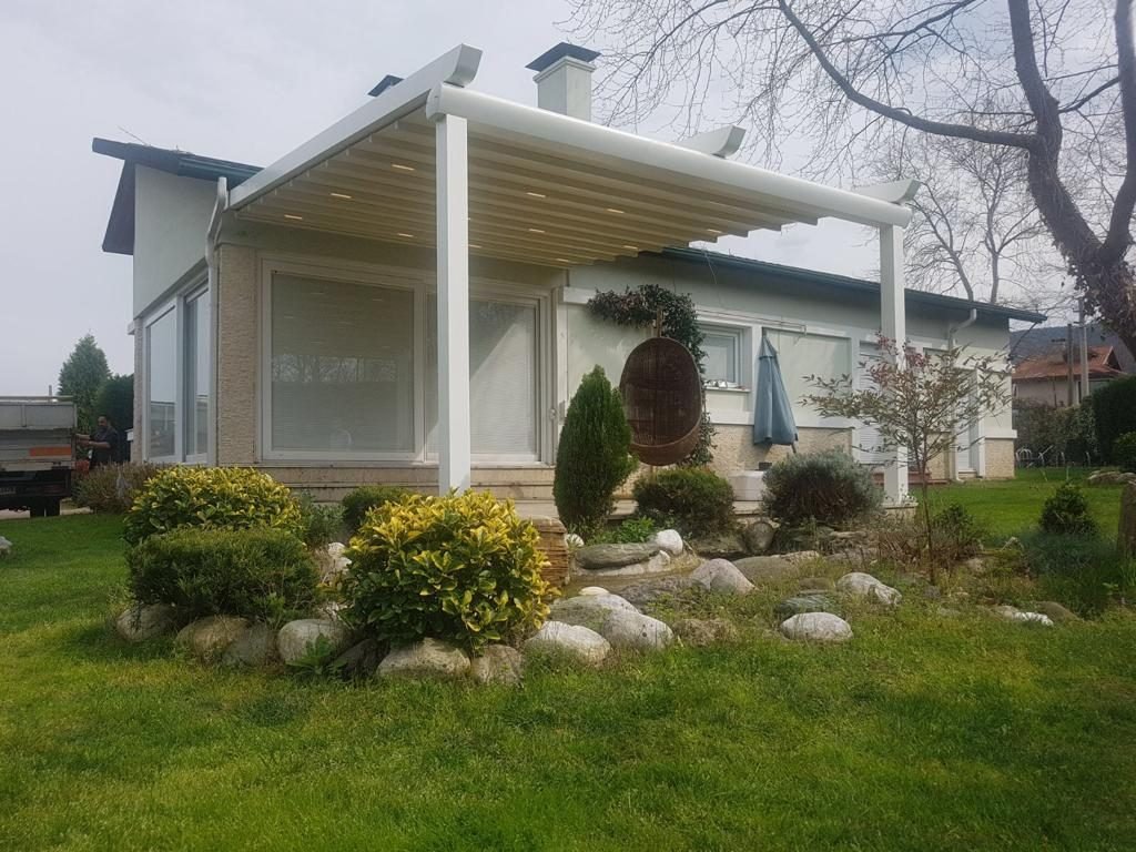 Pergola mit weißem Gestell an einem Wohnhaus im Garten