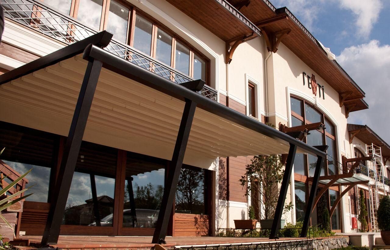 Pergola mit anthrazitfarbenem Gestell vor der Fassade eines Hotels